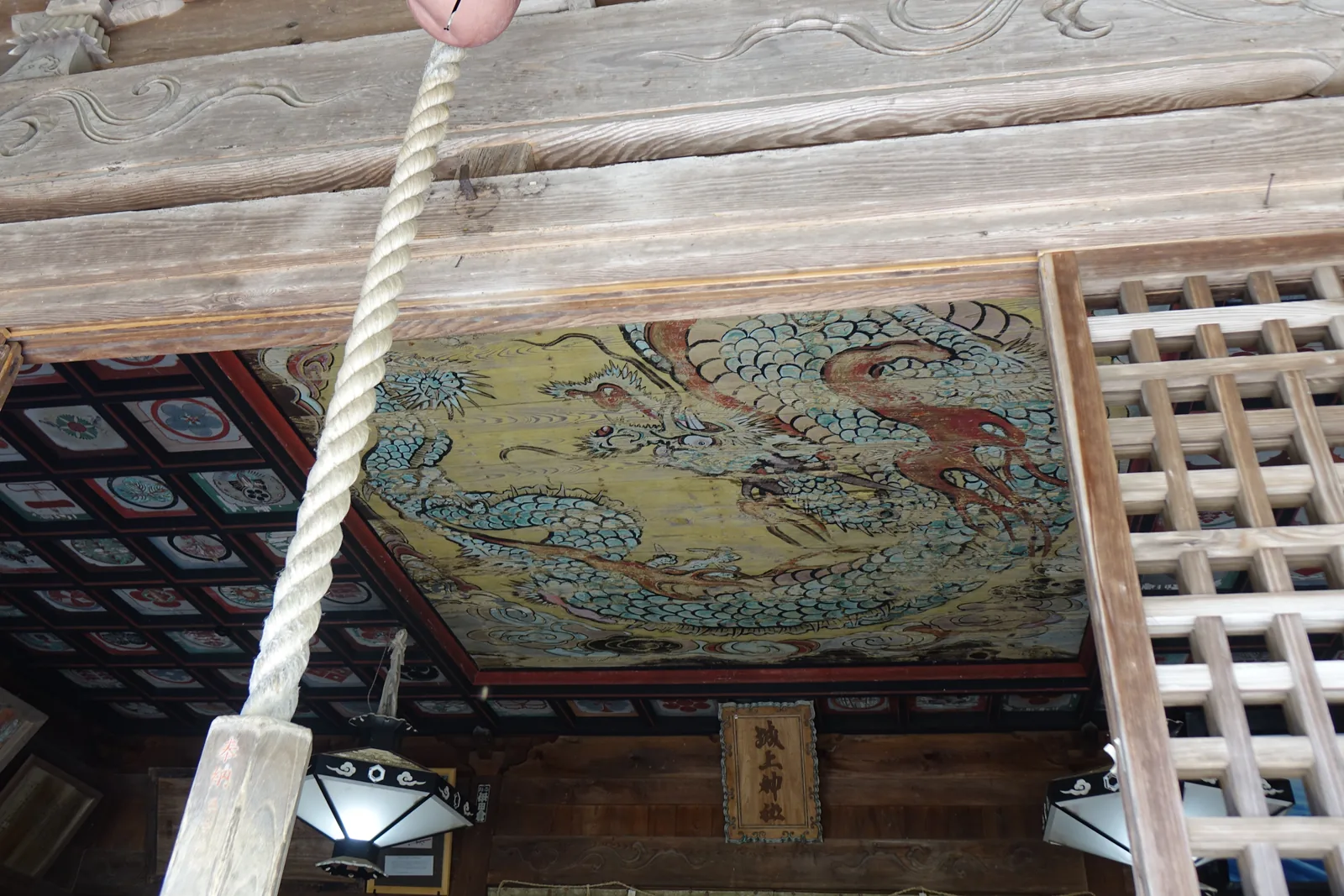城上神社拜殿鏡天井上的極彩色鳴き龍，左右格天井每一格畫一個家紋，下方掛著寫「城上神社」的木製扁額