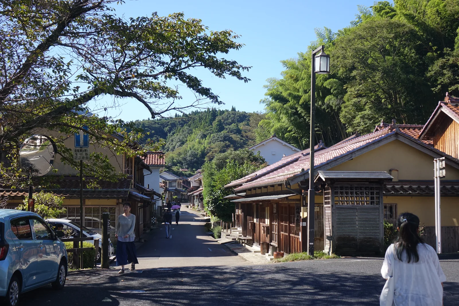 石見銀山大森町的町並み，石州瓦的橘紅色屋頂與土黃色灰泥牆沿著一條路排開，路的盡頭被森林封住