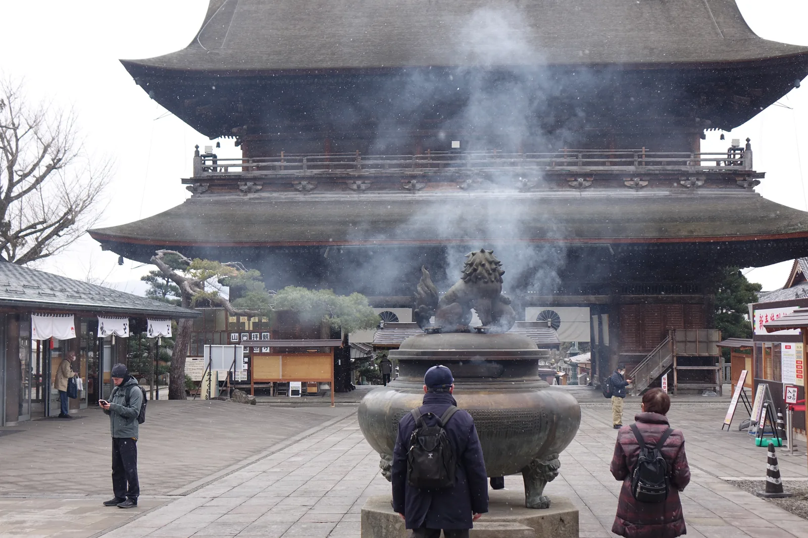 雪中從本堂這一側回望善光寺山門，大香爐的煙與落雪混在一起