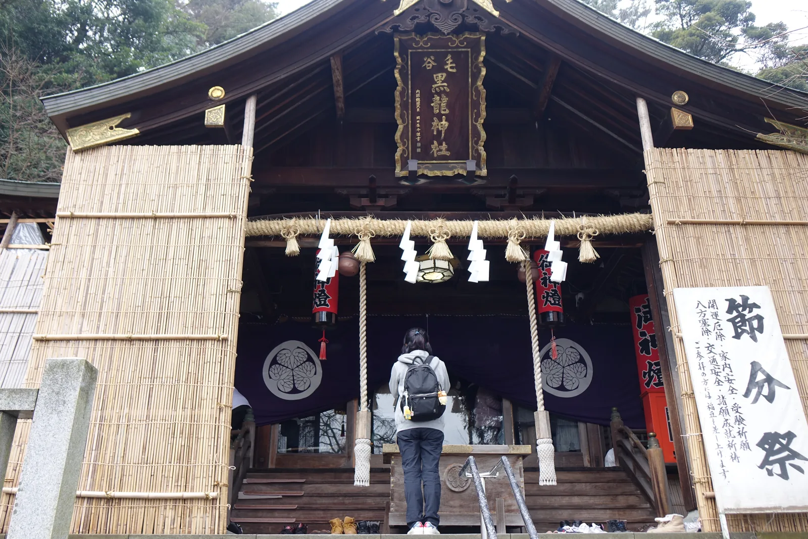 毛谷黑龍神社拜殿正面，兩側以葦簀狀簾子整面圍起，只留中央參拜口，右側立著節分祭木牌