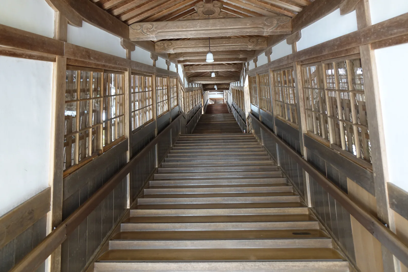 永平寺的廻廊，兩側是障子與玻璃窗，中間一段筆直往上的木階