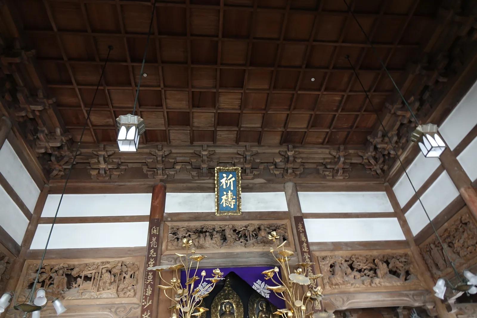 永平寺法堂內部，天井木構往四面撐開，正面高處掛著寫「祈禱」的木札