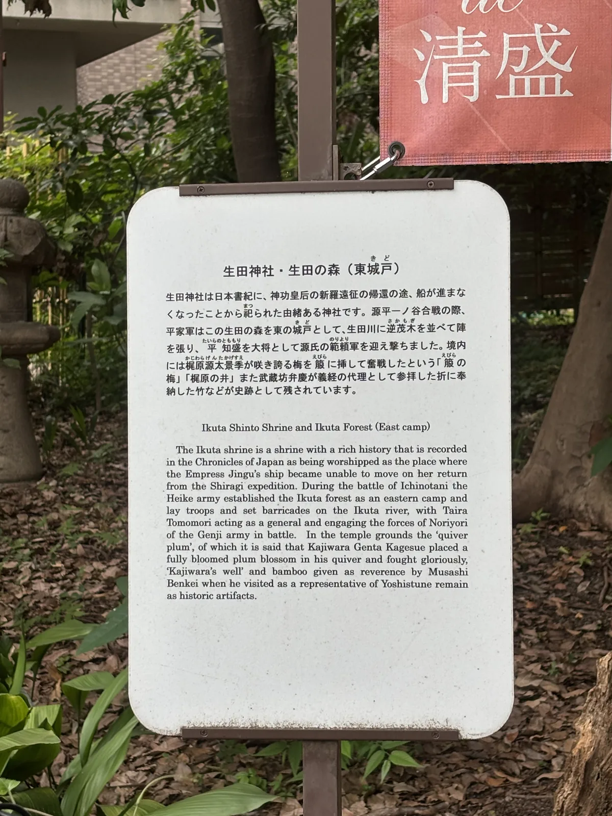 日英對照的解說板，題「生田神社・生田の森（東城戸）」。寫源平一之谷合戰時，平家軍以這片森林為東の城戸，在生田川排下逆茂木布陣，以平知盛為大將迎擊源氏範賴軍。板旁掛一面朱色幟旗，白字「清盛」。