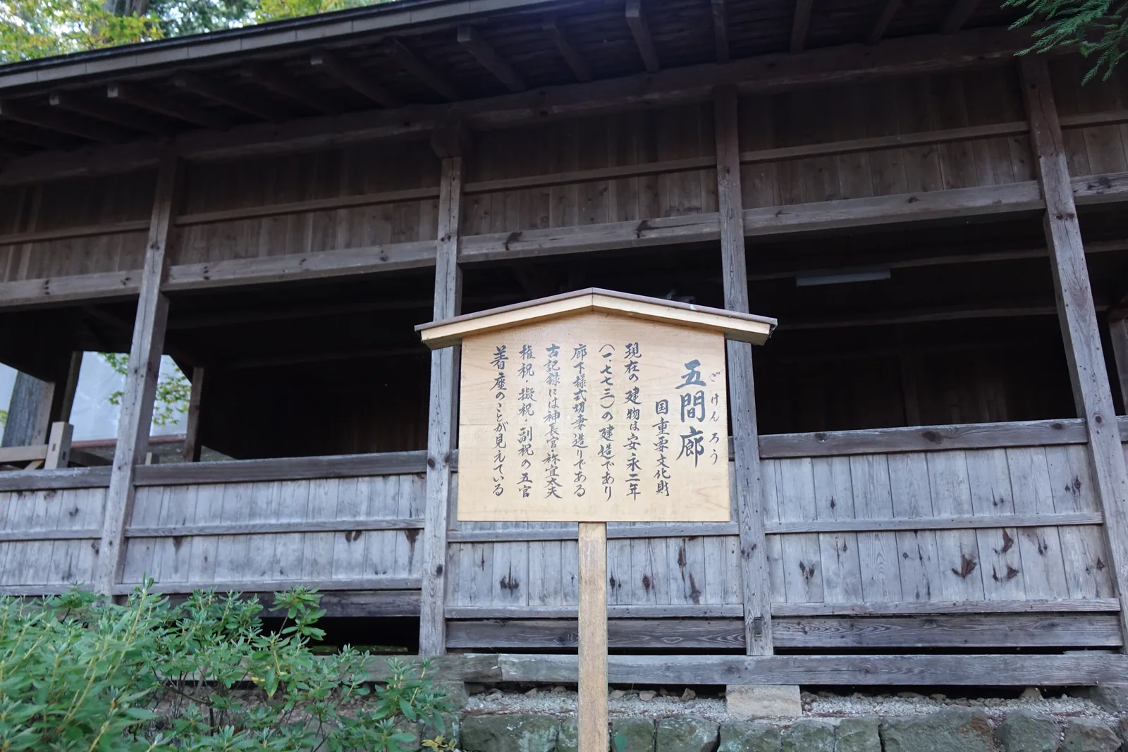 一棟長條形的木造建築，簷下一整排素木（しらき shiraki，不上漆、保留木材原色的作法）的柵欄與板壁；前面立著新的杉木牌，寫「五間廊　国重要文化財」，並記古記錄裡「神長官・祢宜太夫・権祝・擬祝・副祝」五官（五種世襲的神職）在此着座。