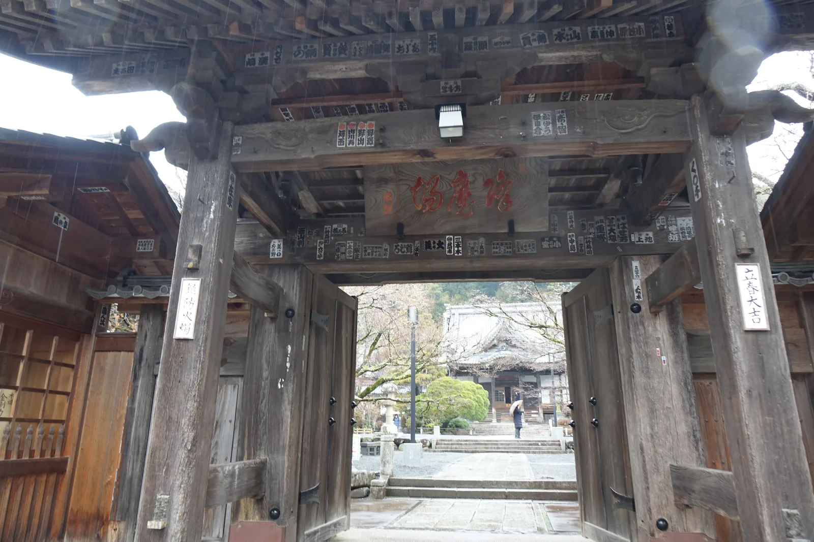 山門的內側，紅字扁額「降魔場」，門扉貼滿千社札