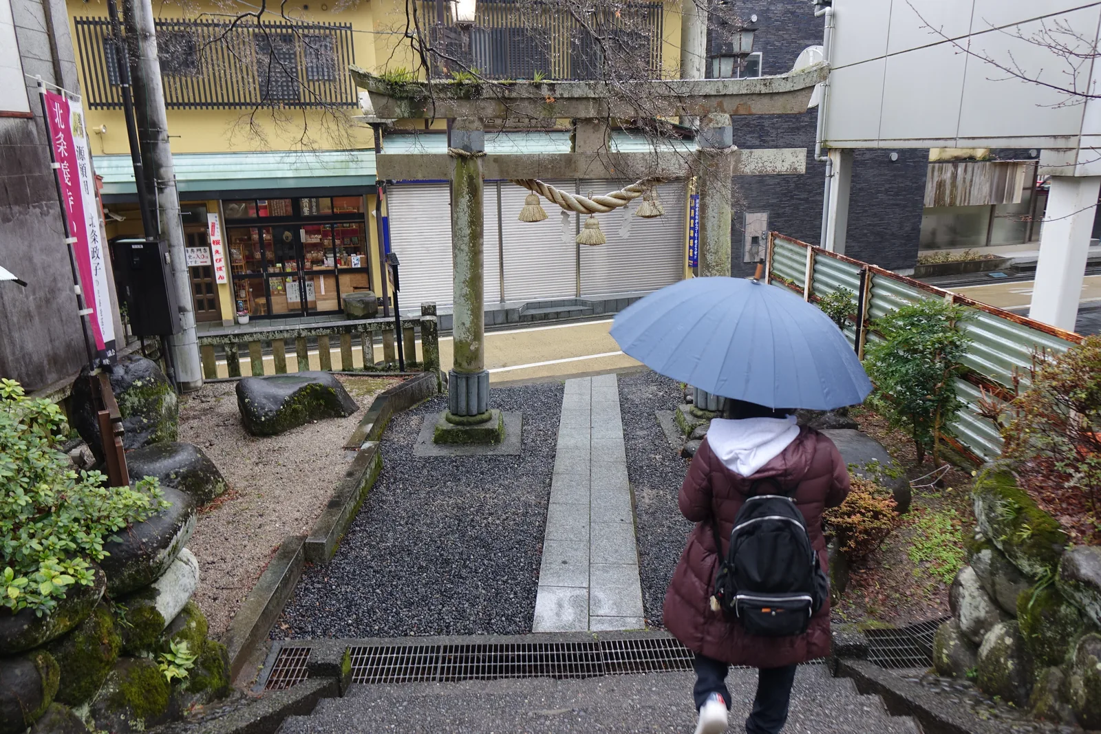 參道盡頭的石造鳥居，石階直接下到縣道，對面就是溫泉街的商店