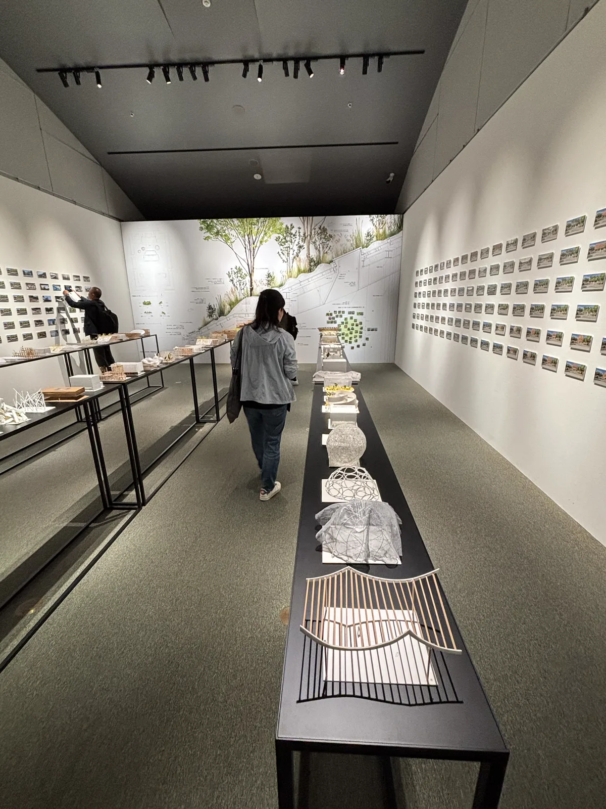 藤本壯介展展場全景，長桌上排著模型，牆面貼滿試案