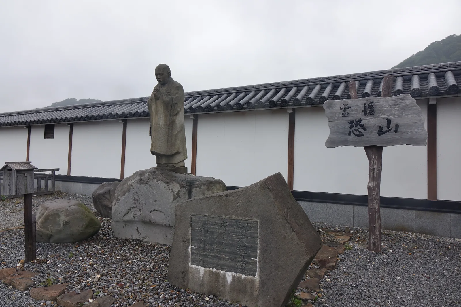 木札題「靈場 恐山」，旁邊立著慈覺大師像與一方刻字的石碑，後面是土塀的側面。開山的傳說從這裡開始，而寺方自己說，近世以前的文書幾乎都不在了。