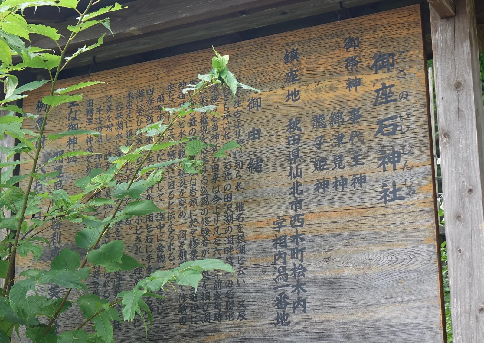 木製的由緒板，標題寫「御座石神社」並注假名「ござのいしじんじゃ」。可讀的欄位有御祭神（事代主神・綿津見神・龍子姬神）、鎮座地（秋田県仙北市西木町桧木内 字相内潟一番地），以及一段講室町時代修驗者創祠的由緒。木面風化，字漆已淡。