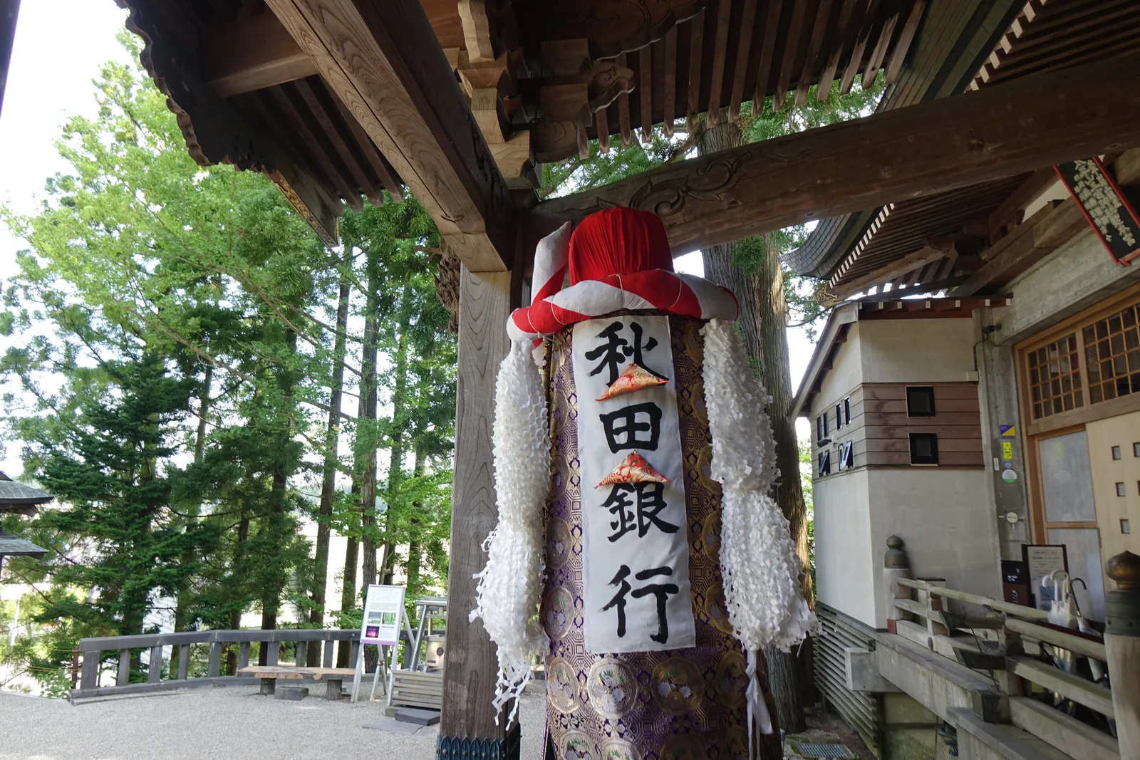 立在授与所簷下的梵天（bonden，神降臨時附著的依代）。頂端的「ほうづき」是紅色的，本體的白布上用紅字染出「秋田銀行」，下方垂著大量白色麻房。