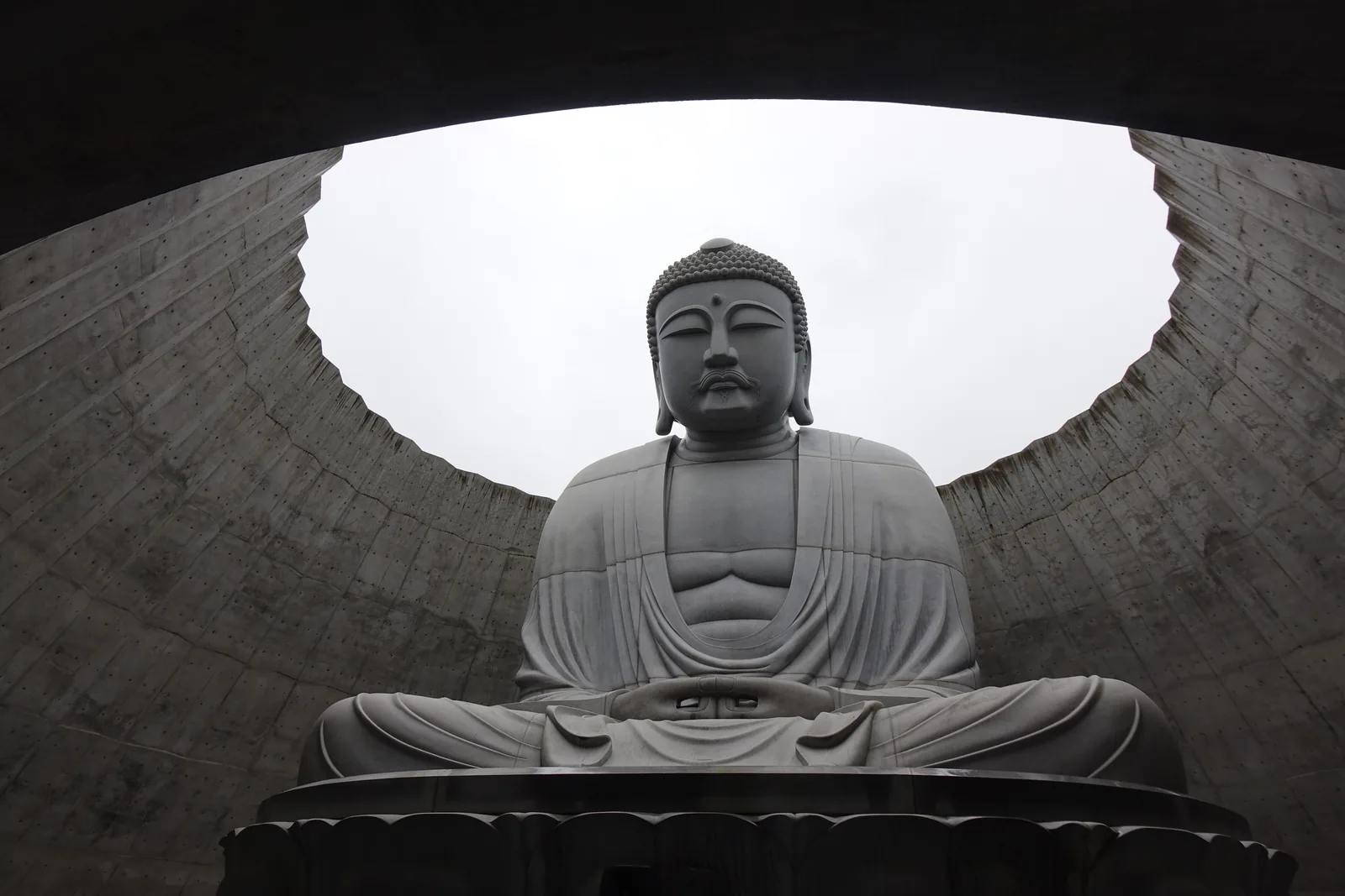 頭大佛殿內部，混凝土穹頂在正上方開一個圓形天窗，天空落進來，石造大佛坐在圓的正中央