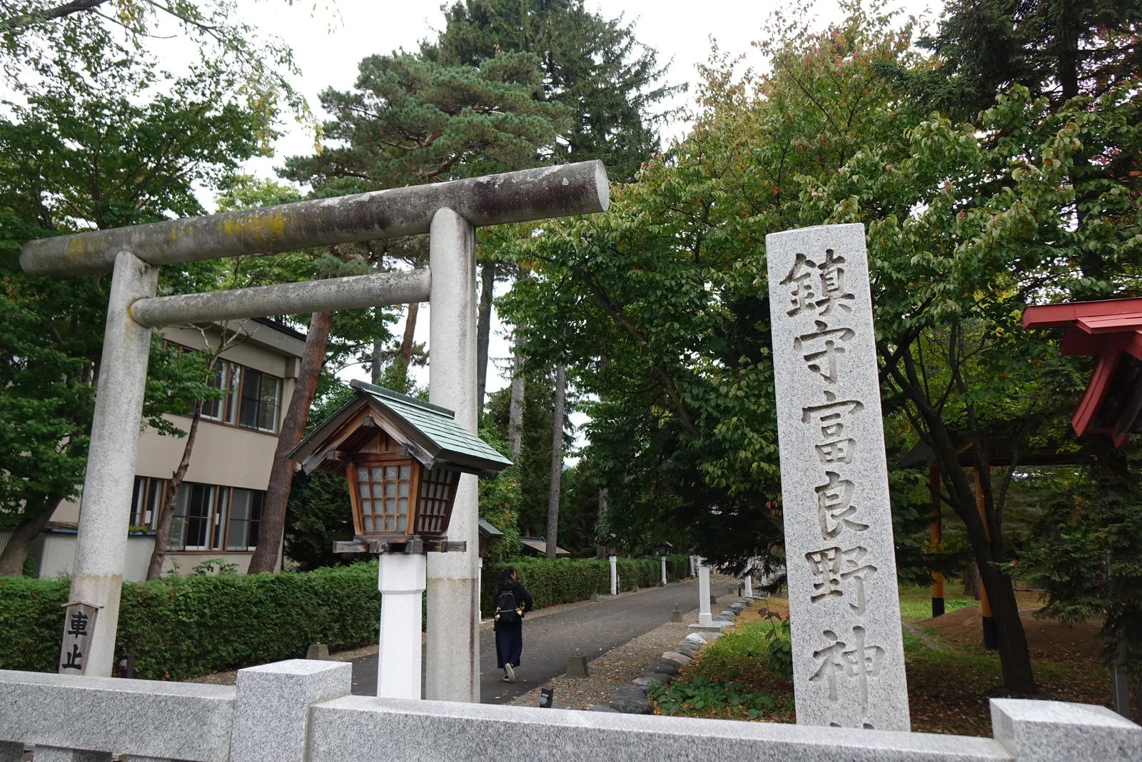 富良野神社的石造社號標，刻著「鎮守 富良野神社」，旁邊是石鳥居與木造燈籠