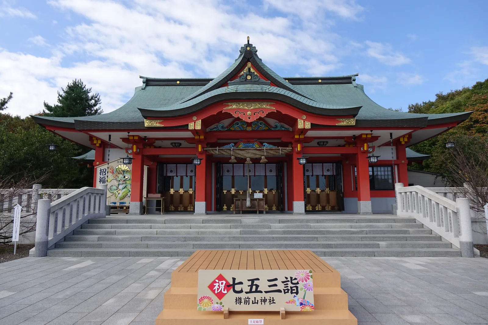 樽前山神社拜殿正面，朱漆的柱與組物，銅板屋頂轉成綠青色，入母屋大屋頂上疊千鳥破風，底下挑出唐破風向拜