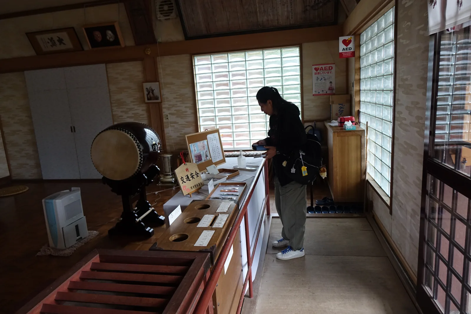 厚岸神社授与所的內部，玻璃磚的窗、木頭的櫃，角落立著一面太鼓，旁邊擺著寫有「祈 交通安全」的木牌