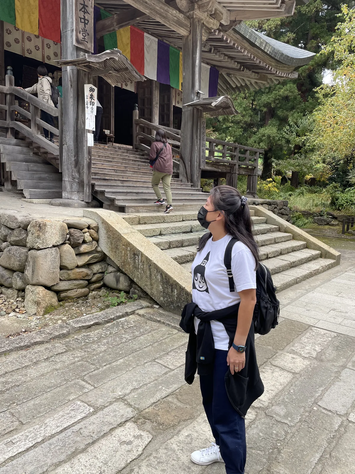 柱子上釘著兩張手寫木牌：一張「御朱印受付　山寺 立石寺」，另一張「四寺廻廊御朱印所」。四寺廻廊串起平泉的中尊寺與毛越寺、松島的瑞巖寺，以及這裡——一塊木牌把一座山標記成跨縣路線上的一站。