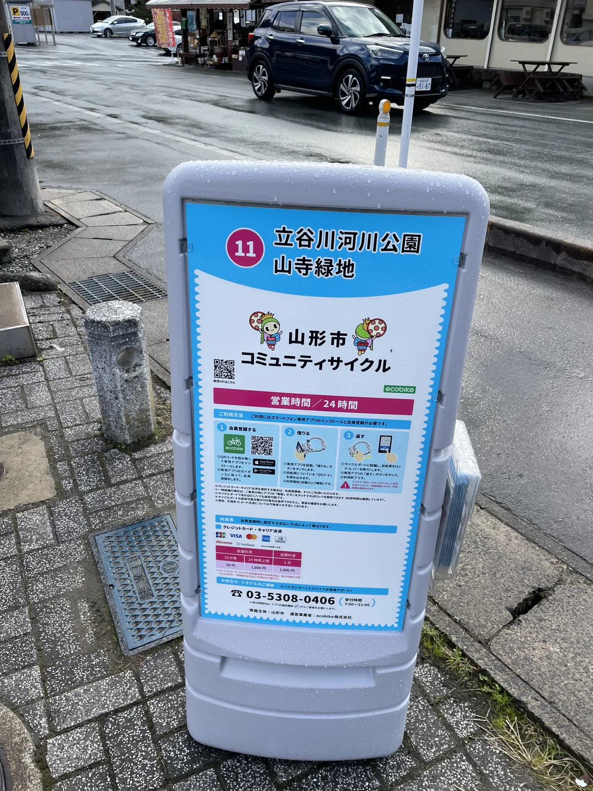 山形市共享單車的第十一號站，二十四小時營業，十五分鐘五十日圓。看板上有雨水的痕跡，路面也還是濕的——那天中午山上下過一陣雨。