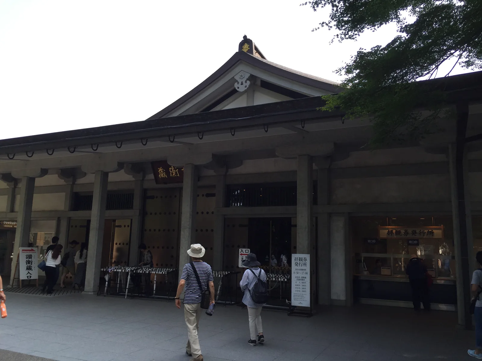 中尊寺讚衡藏：現代的鋼筋混凝土建築，四面斜坡加山牆的大屋頂下掛著扁額，正面是拜觀券的窗口與受付，參拜者在前排隊