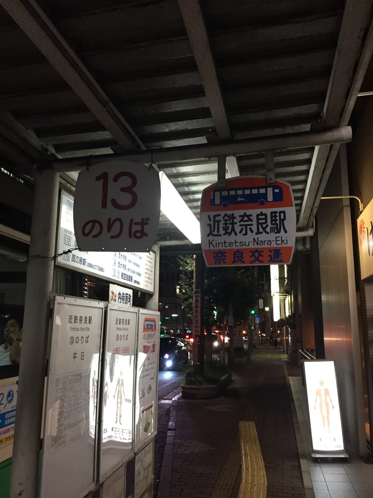 近鐵奈良驛前的十三號乘車處：站牌上方掛著寫「近鉄奈良駅 Kintetsu-Nara Sta.」與「奈良交通」的牌子，夜裡站前的燈全亮著