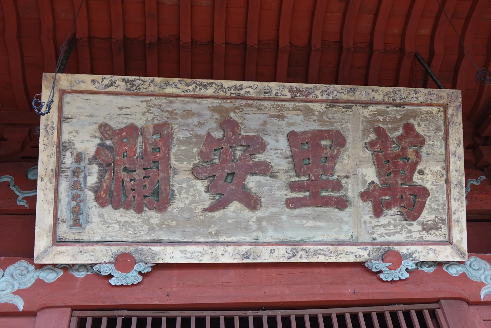崇福寺媽祖堂的「萬里安瀾」扁額特寫，木框上描著雲龍紋