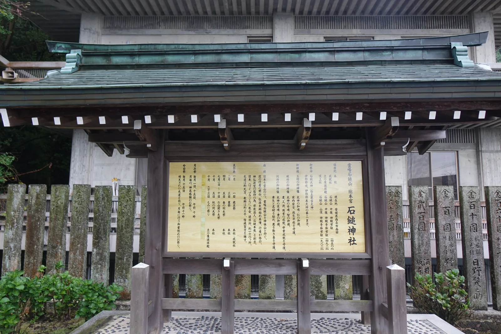 石鎚神社境內的木造覆屋與由緒板，板上記著四座神社的位置與海拔，前方一整排刻著奉納金額的石柱