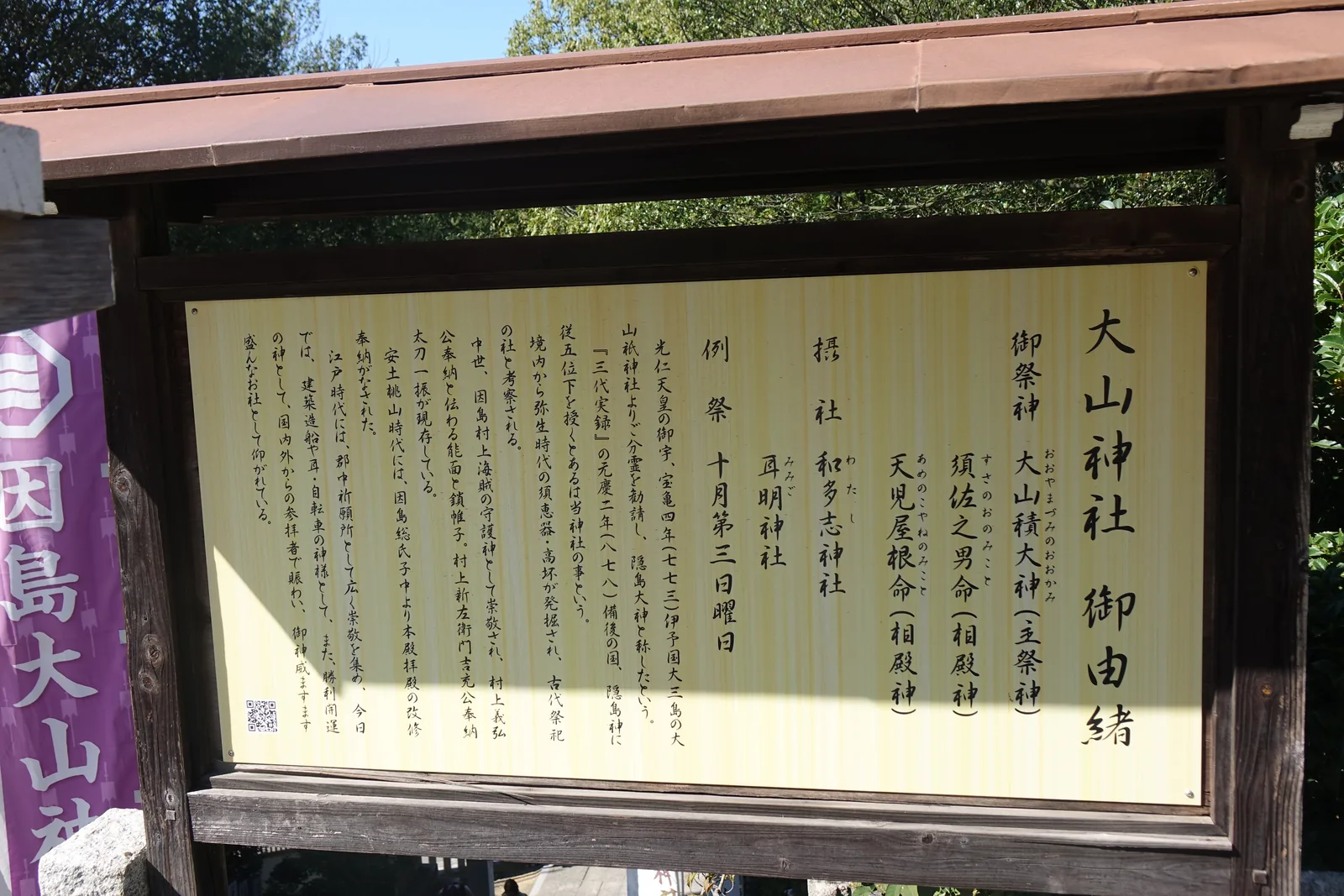 大山神社的御由緒板，木框覆屋下的黃色木板墨書，記寶龜四年自大三島大山祇神社勸請、《三代實錄》的隱島神，以及因島村上海賊奉納的能面、鎖帷子與太刀
