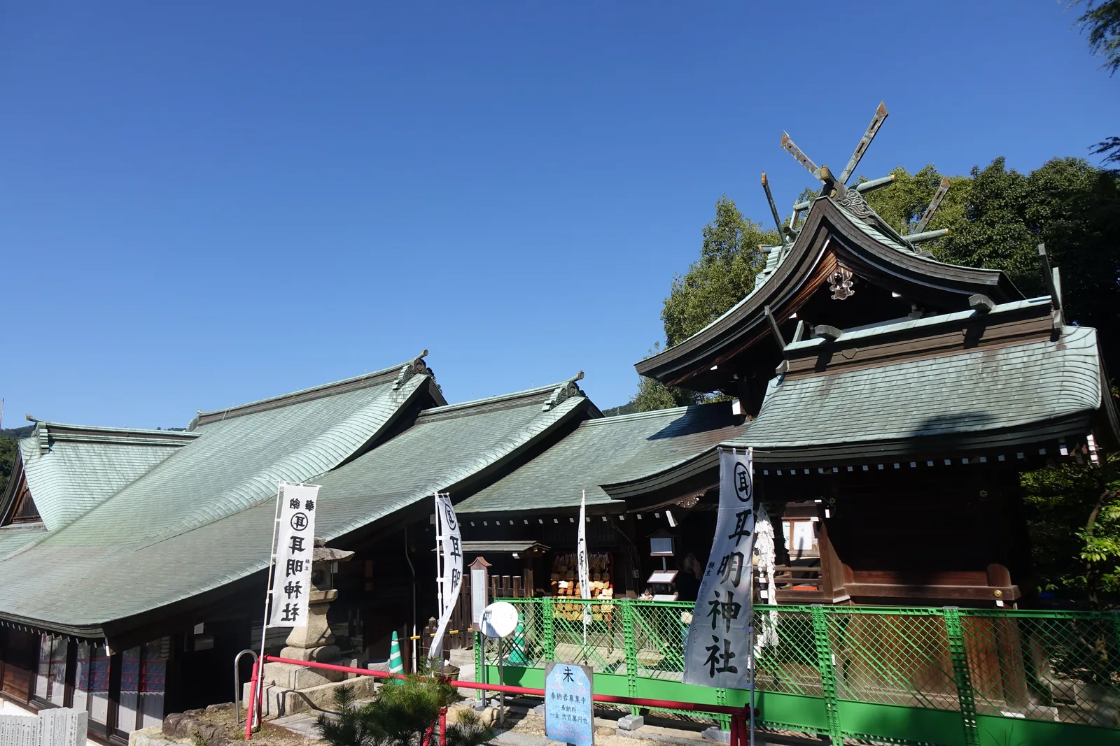 大山神社的社殿群與擋在前面的綠色施工圍籬，屋頂鋪泛綠的瓦，正面一個千鳥破風，白色的幟寫著「耳明神社」
