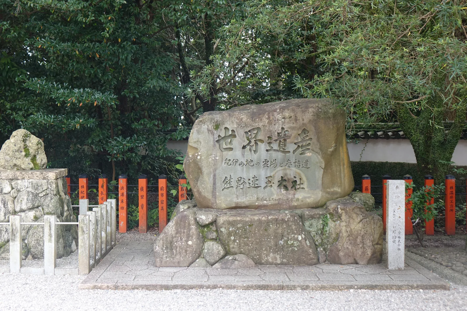 熊野速玉大社境內的世界遺產石碑，一整塊自然石立在朱色的玉垣前，刻「世界遺産　紀伊山地の霊場と参詣道　熊野速玉大社」