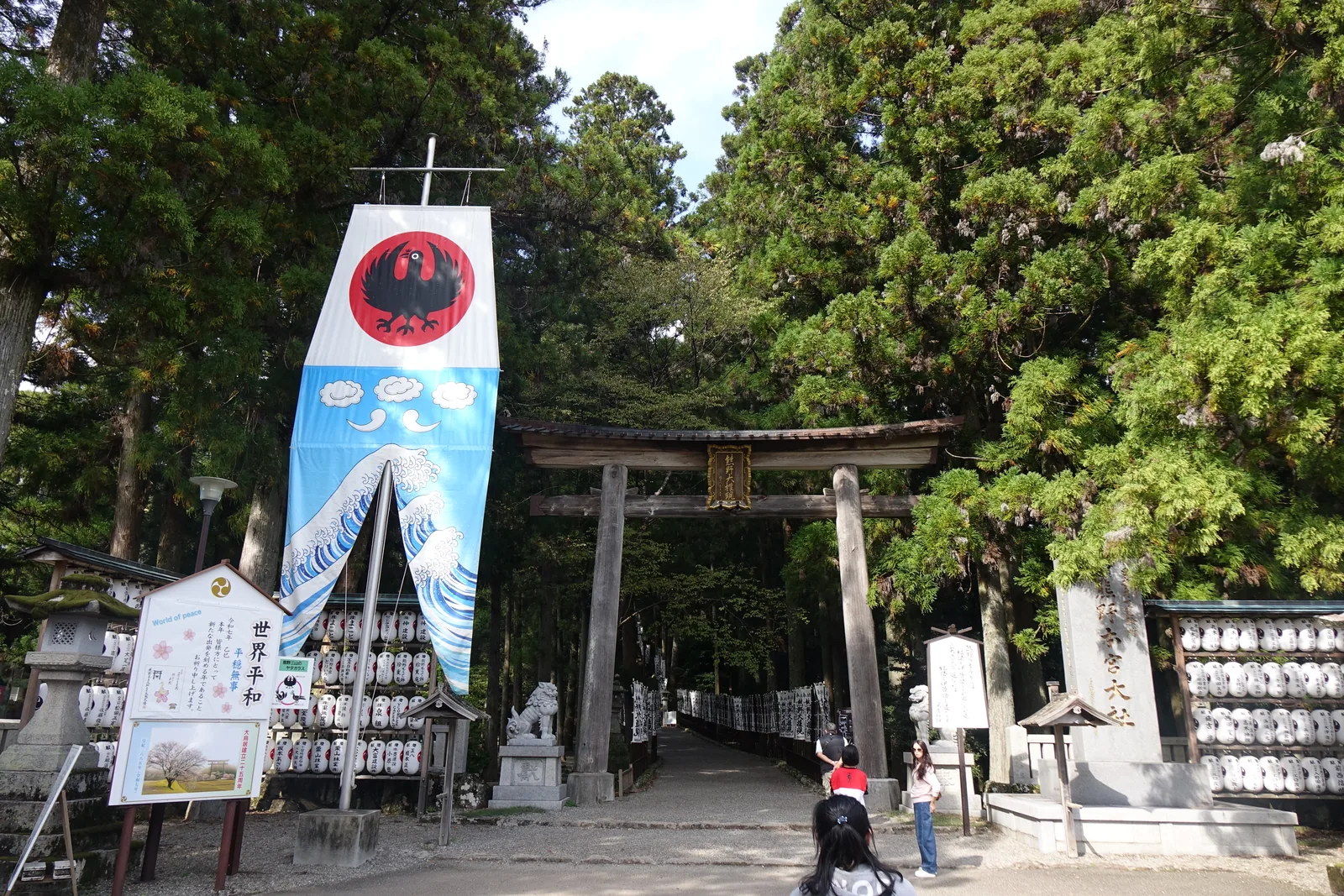 熊野本宮大社參道入口的一之鳥居與八咫烏的幟，白底藍浪配一隻黑色的三足烏