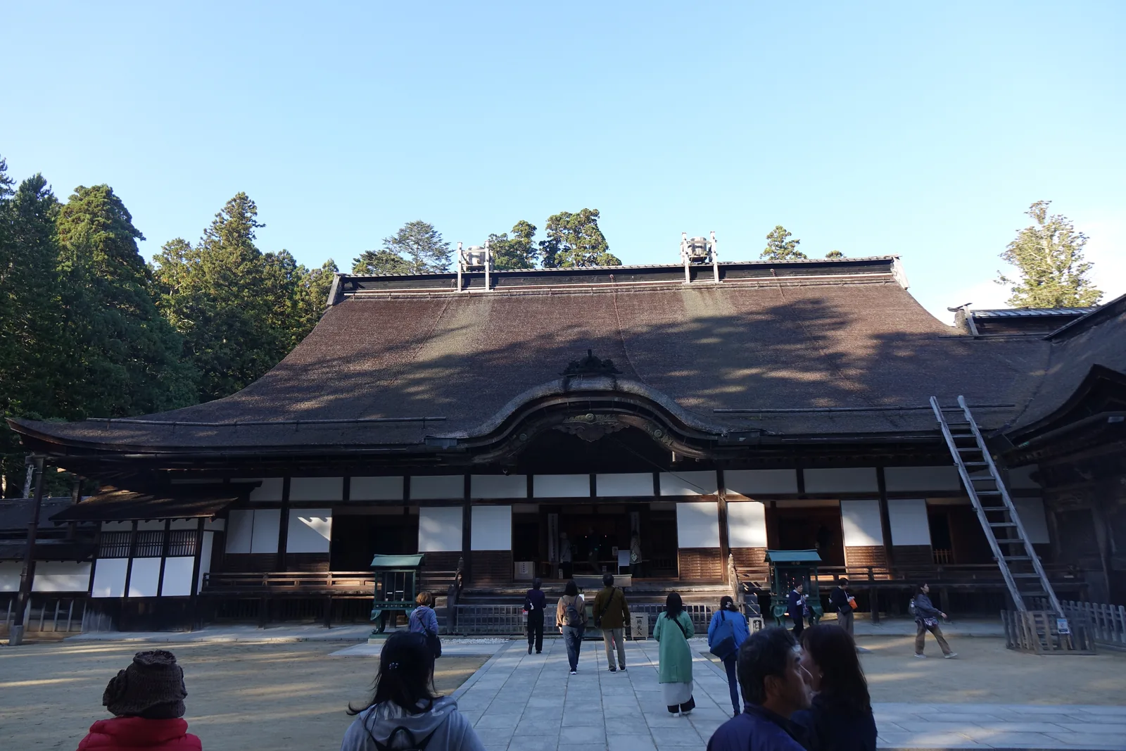 金剛峯寺大主殿正面，檜皮葺的大屋根，棟上放著兩具天水桶，右側斜靠一具長梯