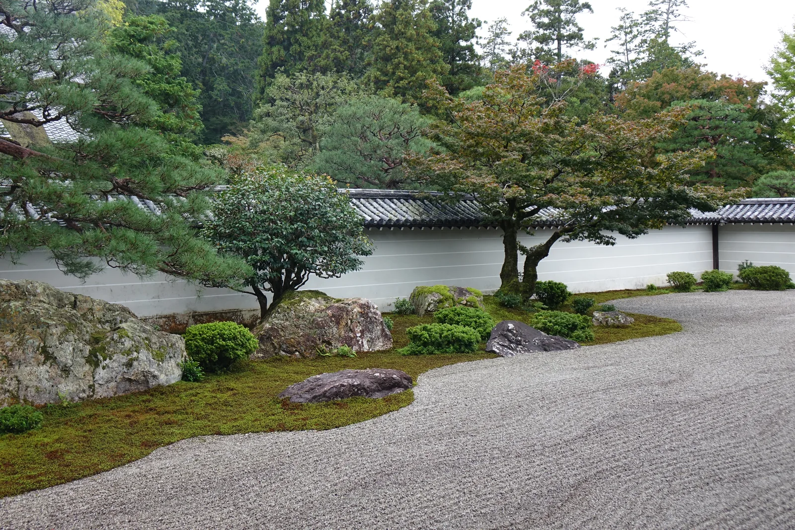 南禪寺方丈庭園「虎の子渡し」：大片耙過的白砂，石組全都集中在左後方沿著白色築地塀排列，牆後是東山的樹林