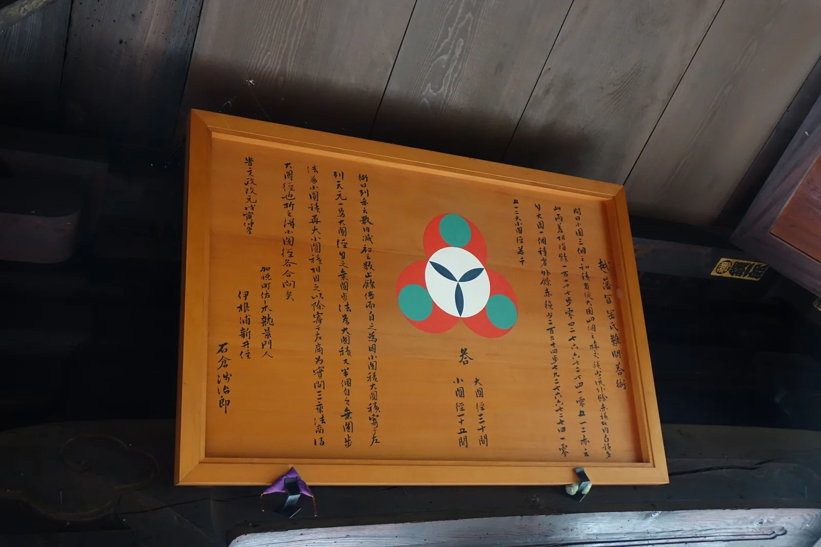 掛在文殊堂外簷下的算額：木框中央畫著三個紅綠相扣的圓，兩側是漢文的問與術，中央下方寫「答　小圓徑十五間　大圓徑三十間」
