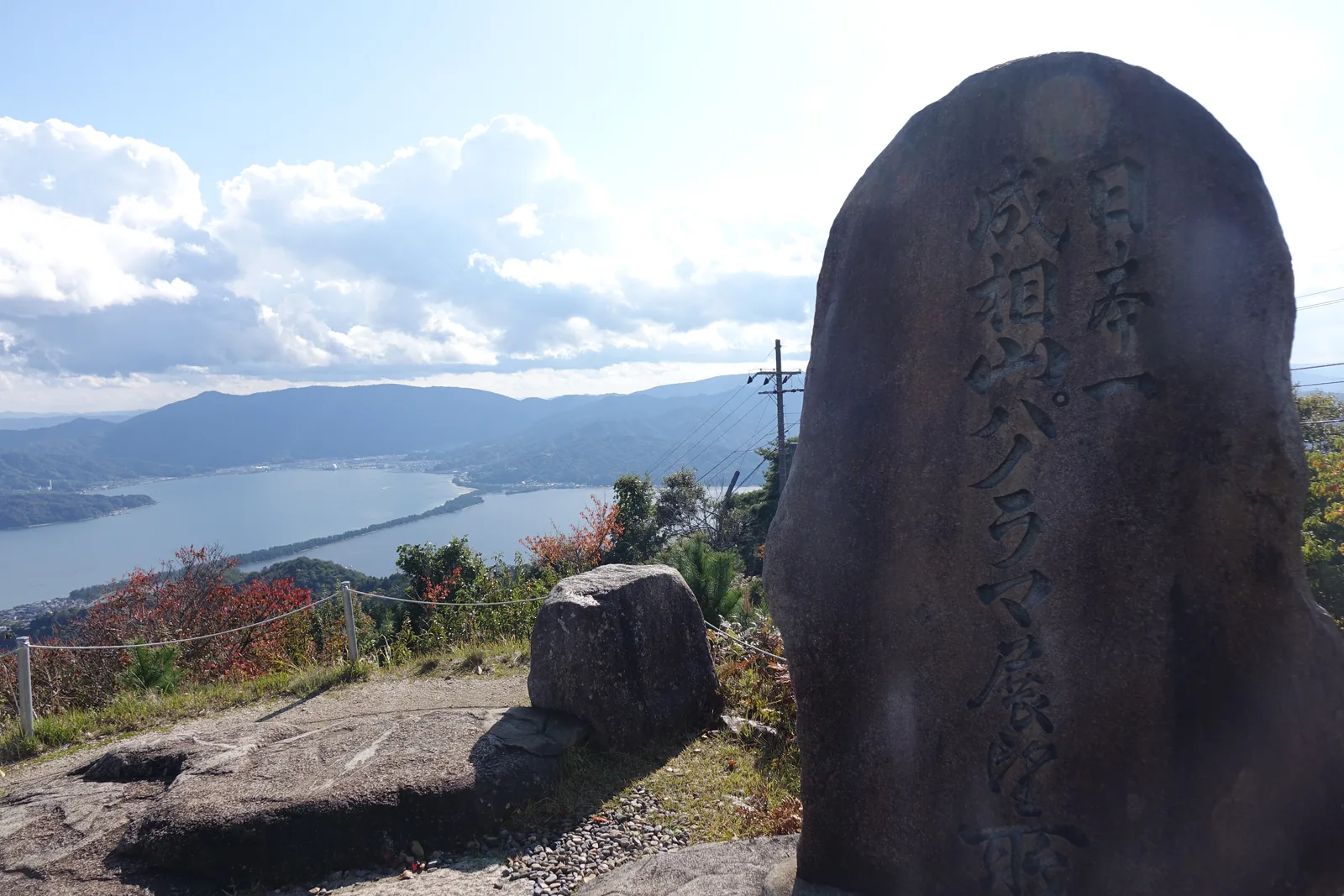 成相山全景展望所的石碑，碑面刻著「日本一　成相山パノラマ展望所」，後方是天橋立與宮津灣