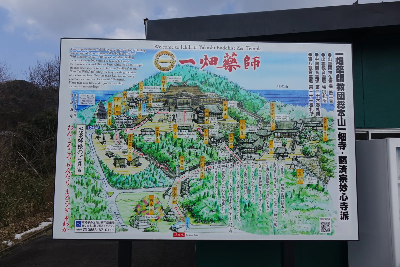 停車場旁的境內鳥瞰圖，寺方設置，附英文。右欄直書「一畑薬師教団総本山　一畑寺・臨済宗妙心寺派」（一畑藥師教團總本山、一畑寺、臨濟宗妙心寺派），並列出四處靈場札所。圖上兩段石段的段數都標了：下段一千一百三十八級、上段一百四十級。左欄直書藥師如來的真言「おんころころ せんだり まとうぎ そわか」，左上角另標「お薬師様出現の地　赤浦海岸」——本尊出現的地方在圖外的海邊。