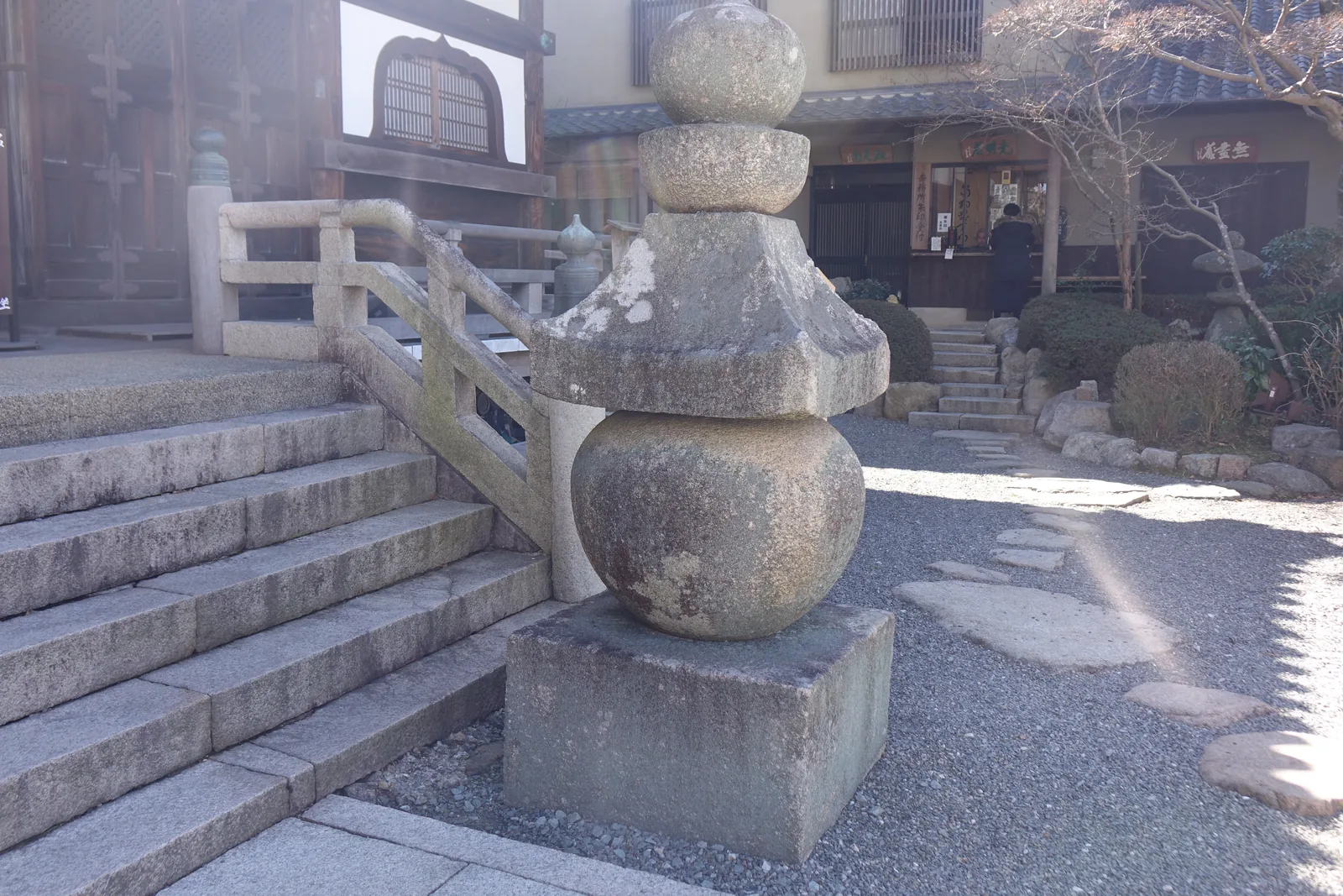 本堂石階右側的五輪塔，花崗岩，立在方形的地輪上，由下而上是球形的水輪、屋根形的火輪、半球的風輪與寶珠形的空輪。火輪的簷角缺了一塊，塔身長滿苔與地衣。神戶市的說明板記兩基分別是二四一公分與二五四公分，造立於鎌倉時代中期至後期。後方是寺務所與納經所，一位參拜者正站在櫃檯前。