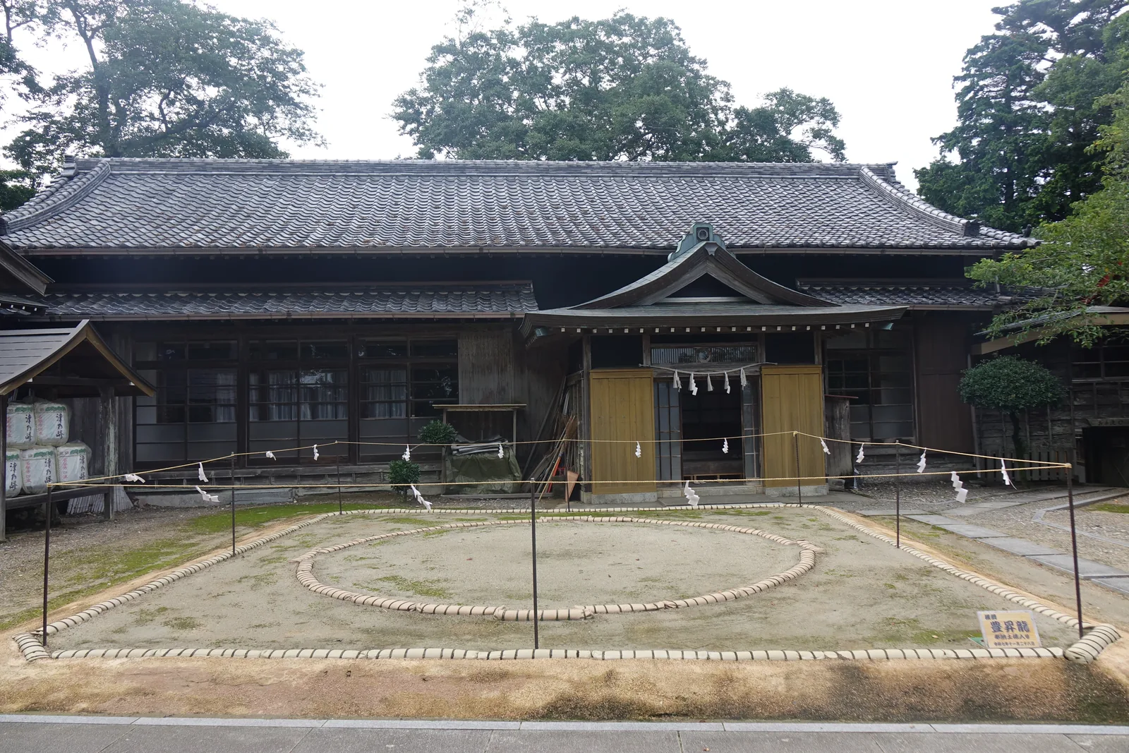 津峯神社境內另一處院子裡的土俵：俵繩圈成一個圓，四角拉繩立柱，面對一棟大型的瓦葺建物