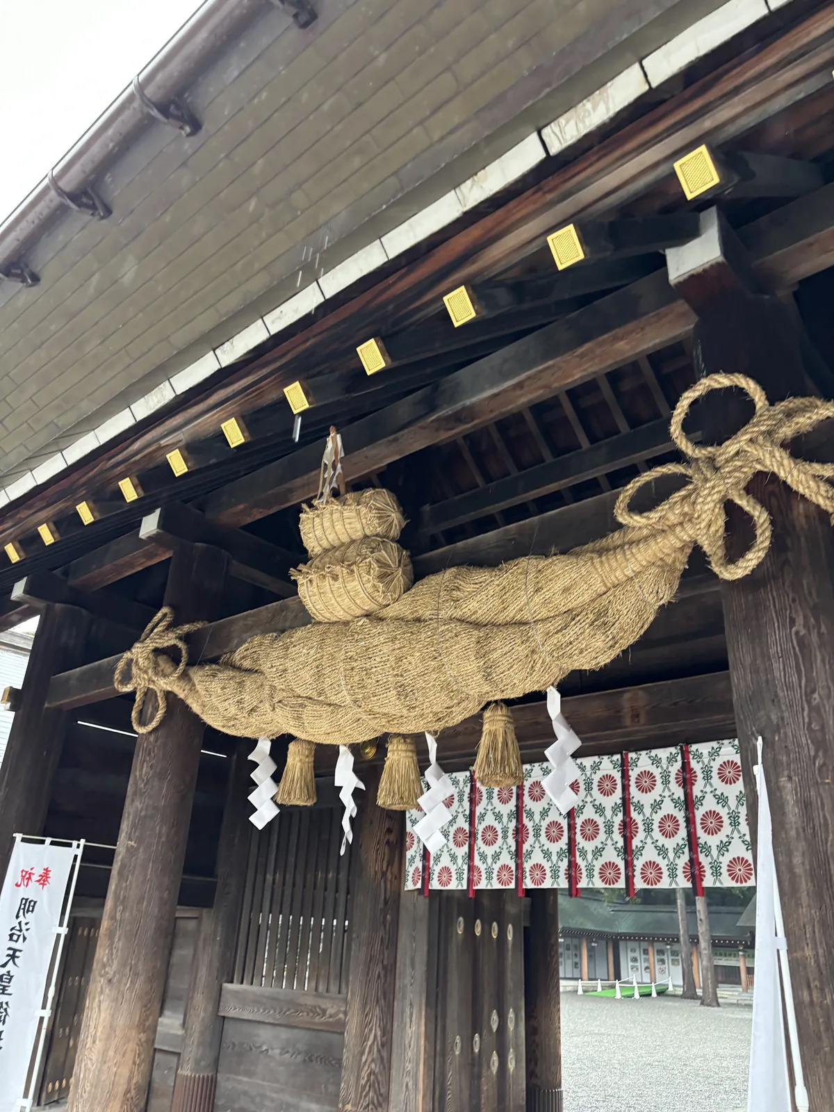 從正下方看北海道神宮神門的大注連繩，兩端收細再捲成環