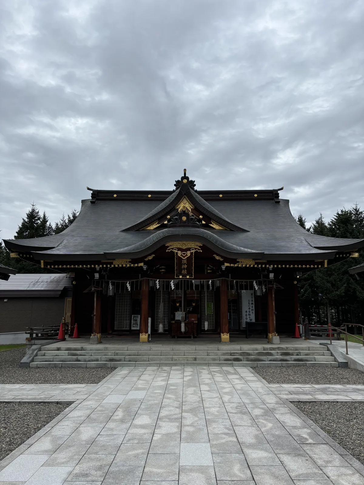 美瑛神社社殿正面，黑色入母屋造屋頂，中央起千鳥破風，其下接唐破風向拜，雕刻全部貼金