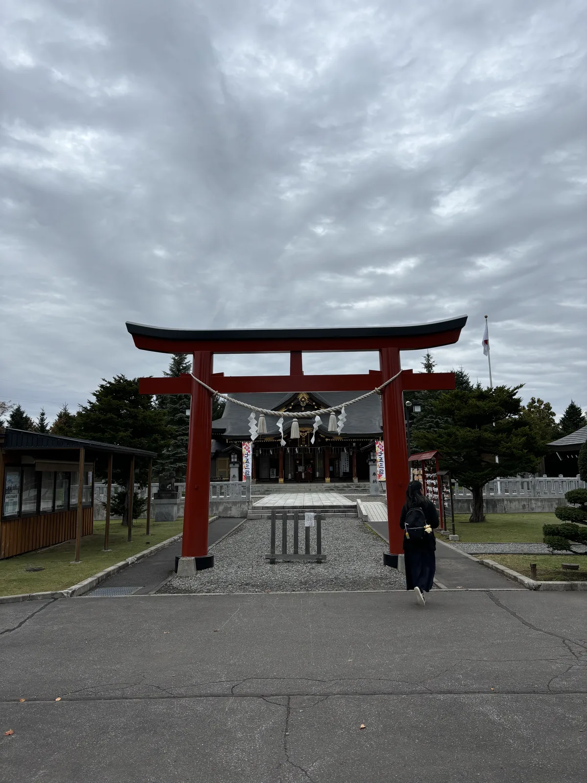 美瑛神社朱塗的明神鳥居，笠木染黑，中央懸注連繩，鳥居後是筆直的石鋪參道與社殿