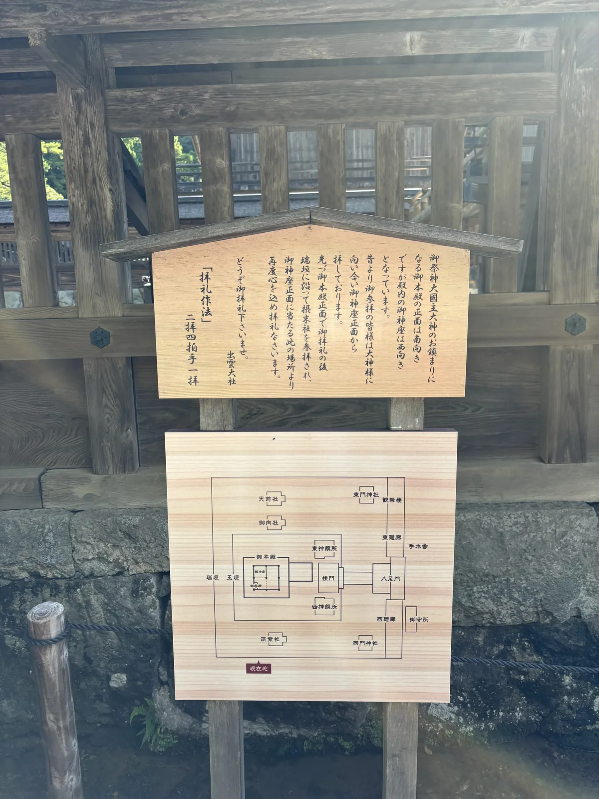 出雲大社瑞垣西側的社方掲示，說明本殿正面朝南而殿內御神座朝西，下方附一張境內平面圖