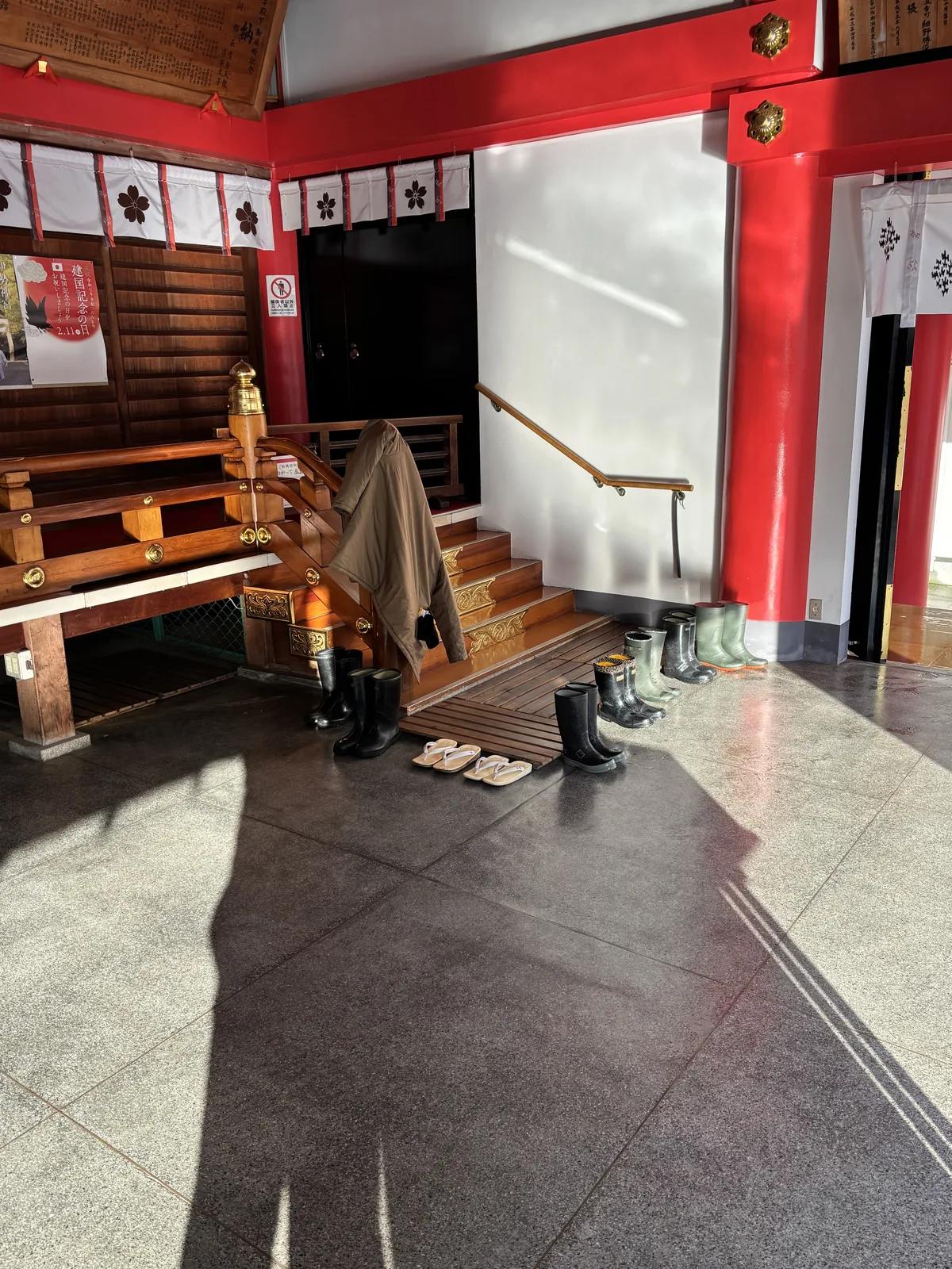 日枝神社昇殿口的磨石子地坪，木階前排著長靴與一雙白草履