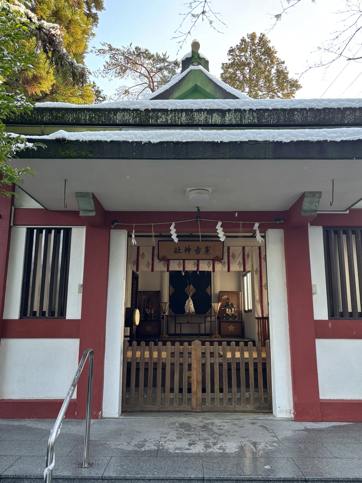 麁香神社的社殿，朱柱白牆的混凝土造，扁額刻「麁香神社」，格子門後看得見兩尊神像