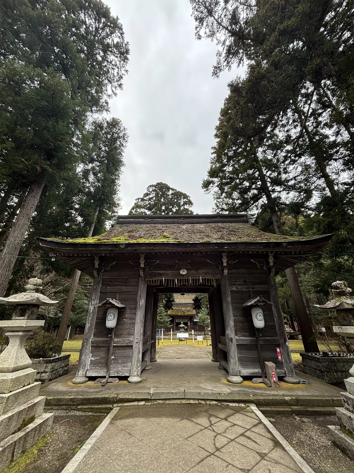 若狹姬神社隨神門正面，檜皮葺的屋頂上長滿厚厚一層苔，左右各立一基石燈籠