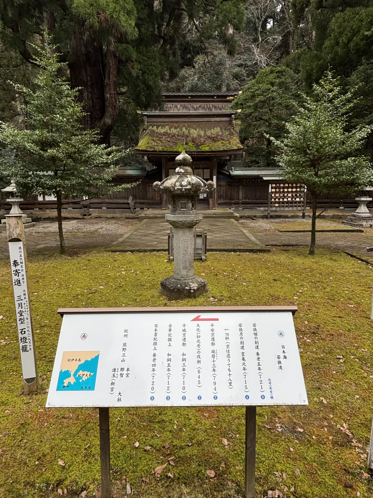 從若狹姬神社境內看神門與本殿的覆屋，屋頂同樣覆著苔，前景是一基石燈籠