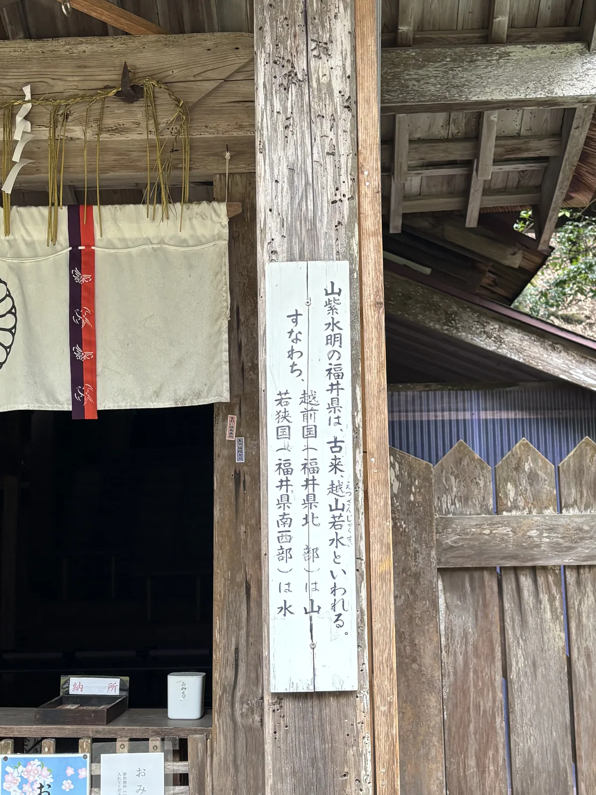 若狹姬神社授与所旁柱上的木札，寫著越山若水，上方垂著注連繩與紙垂