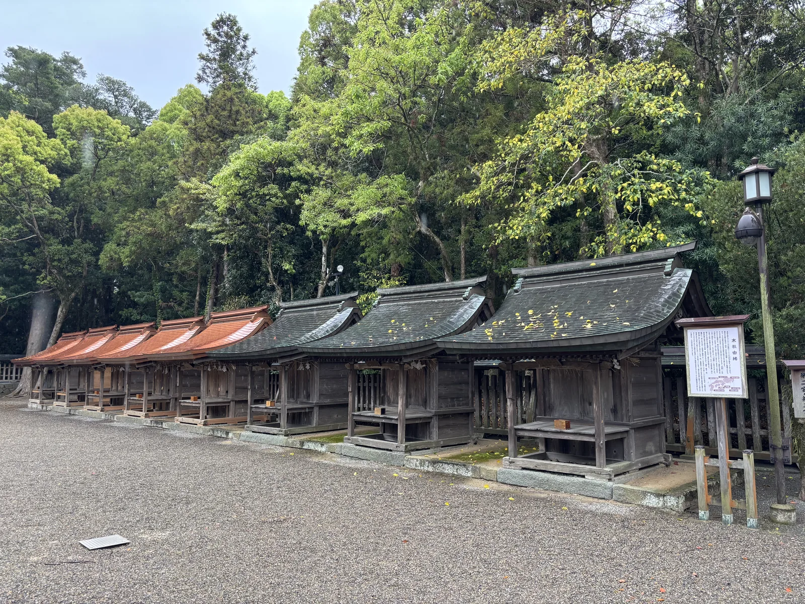 一整列末社的屋頂，前景是氧化成暗綠的舊銅板，後段是新換上的橙紅色銅板