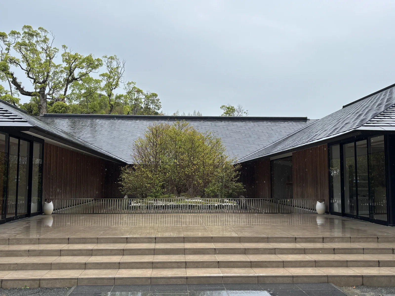 祈願殿的中庭，兩翼的深色屋頂夾著一座種著樹的白砂庭園