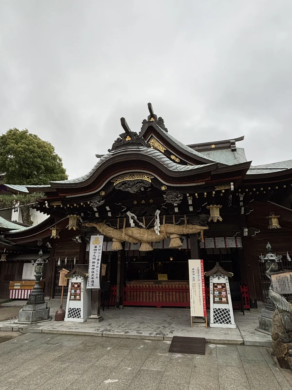 櫛田神社的拜殿正面，粗大的注連繩橫過簷下，左側立著第四十九回式年遷宮的白幟