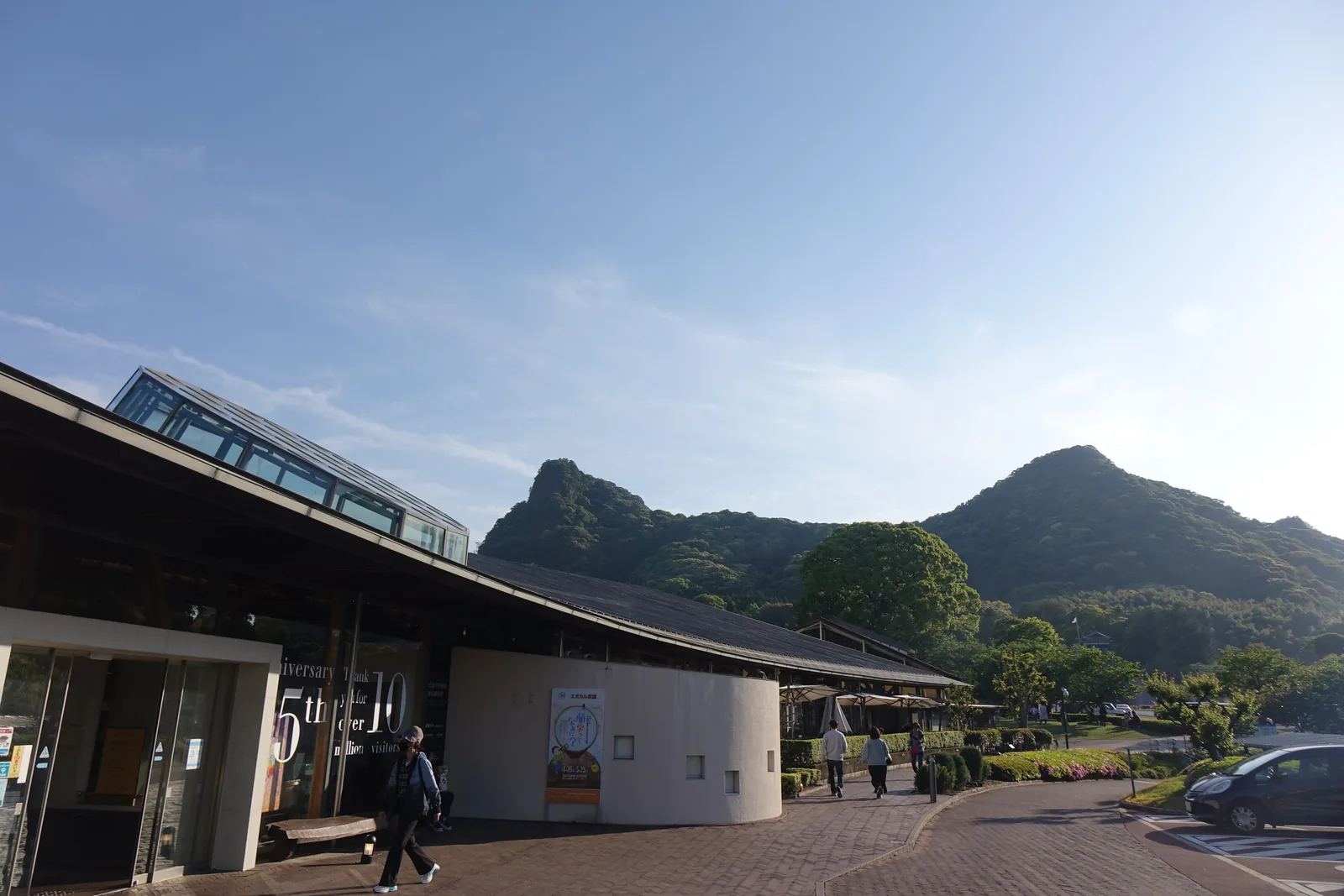 武雄市圖書館的入口，長而低的深色屋簷，後方是御船山的兩個山峰