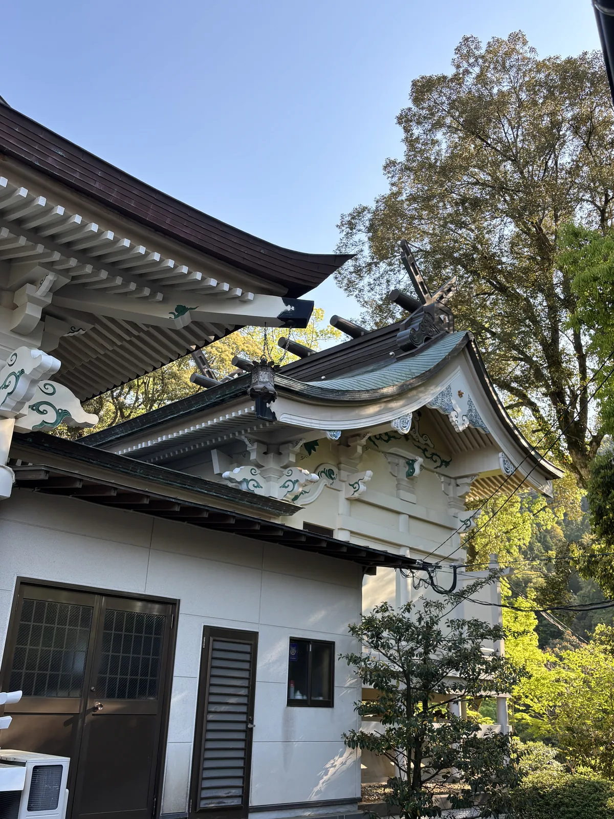 拜殿屋簷底下的雕刻近景，白底上以青綠色描邊的雲形木雕層層外挑
