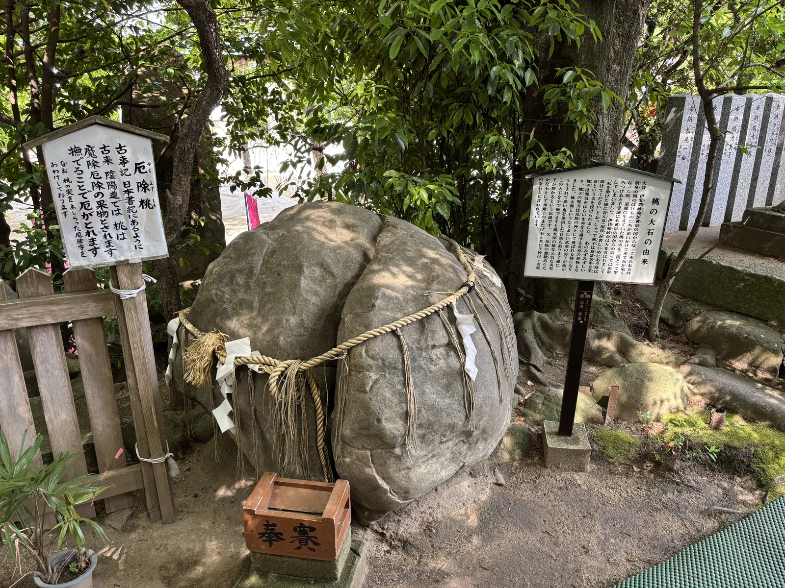 昊天宮境內的桃の大石，形狀像剖開的桃，腰上繫著注連繩與紙垂，前方擺著木製賽錢箱，左右各一塊說明看板